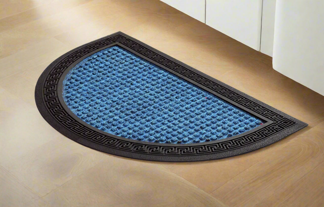 
                      
                        A halfmoon shaped blue bath mat with a black border, placed on a tiled floor.
                      
                    