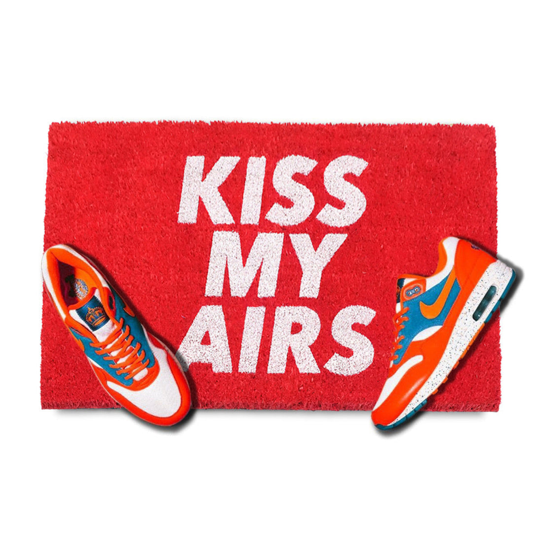 Red doormat with 'KISS MY AIRS' text and orange and blue sneakers on a white background