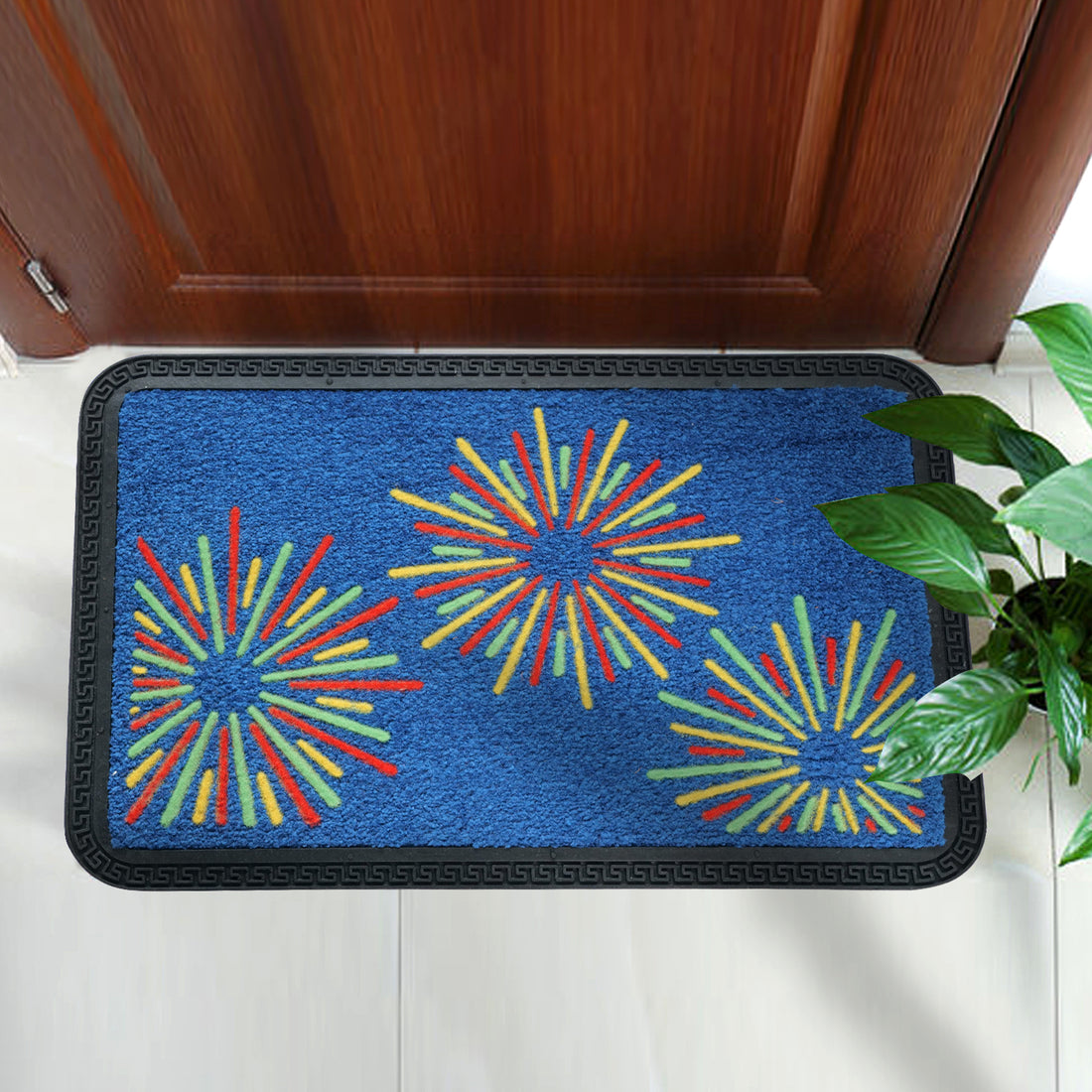 A rectangular blue mat with colorful geometric patterns, placed on the floor near a door entrance, with a black mattress-like backing and a small potted plant to the side.
